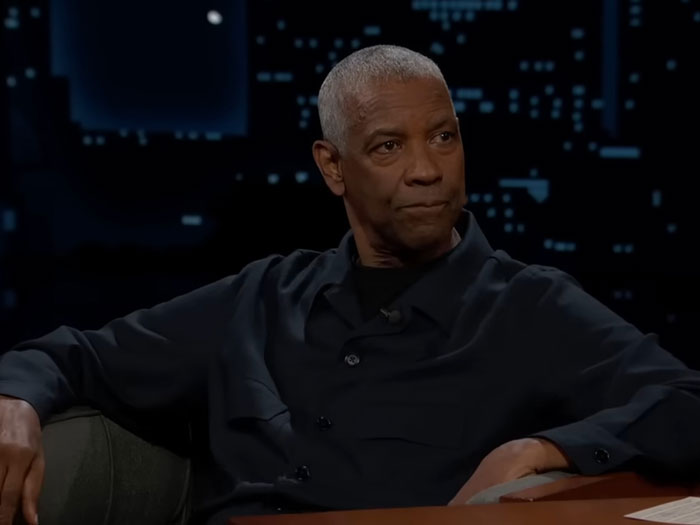 Denzel Washington seated in a dark shirt during a nighttime interview revealing the correct way to pronounce his name. Denzel Washington seated in a dark shirt during a nighttime interview revealing the correct way to pronounce his name.