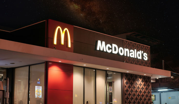 McDonald's restaurant at night with illuminated golden arches and signage under a starry sky showcasing brilliant loopholes concept.
