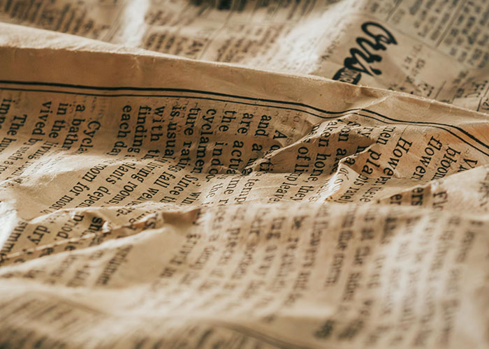 Crumpled newspaper pages with visible text showcasing a hidden gem discovery concept for new homes.