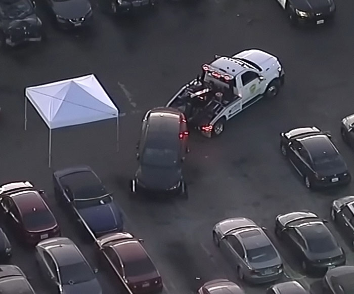 Tow truck removing a Tesla registered to singer at a parking lot after decomposing body was found inside the abandoned vehicle.