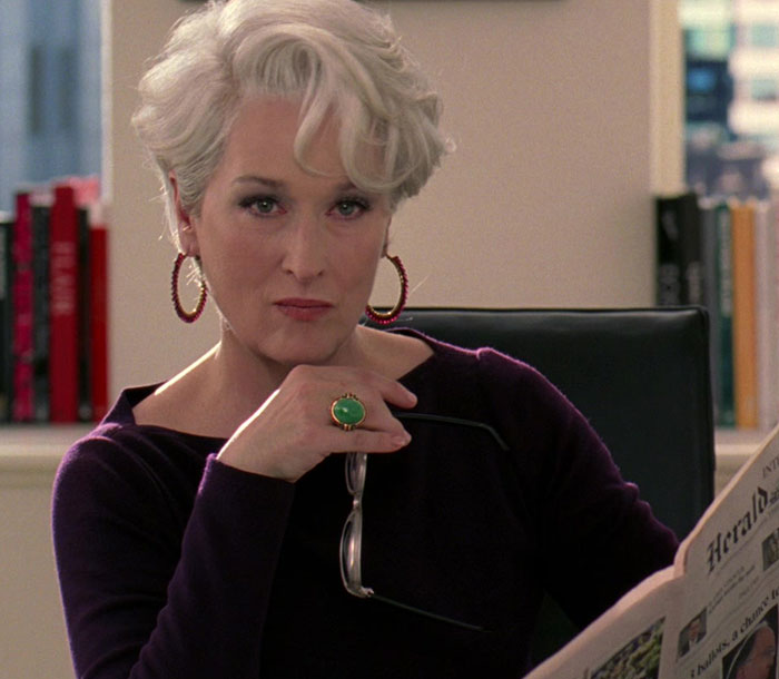 Anna Wintour holding glasses and reading a newspaper, expressing thoughts related to The Devil Wears Prada.