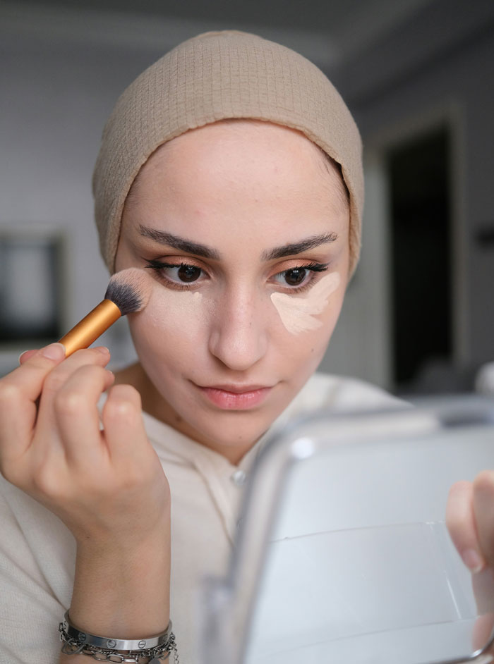 Woman applying makeup with a brush, illustrating unexpected things men didn’t know about women until dating them.