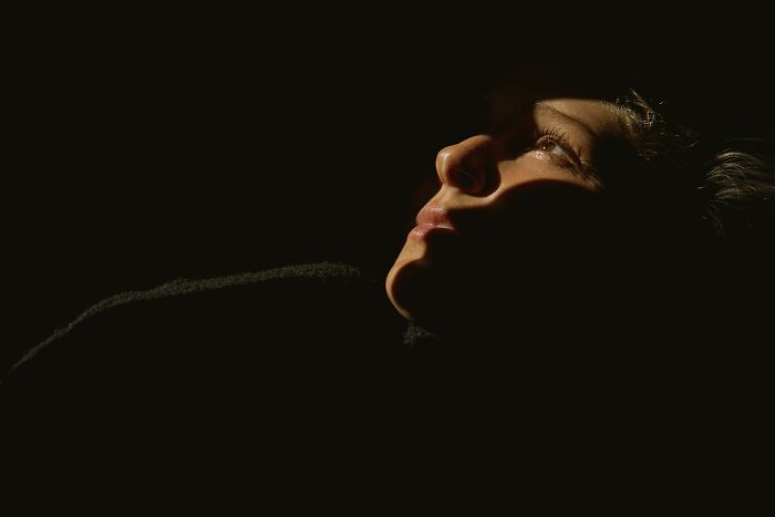 Close-up of a person&rsquo;s face emerging from darkness, illustrating trust your gut feeling and possible precognition concepts.