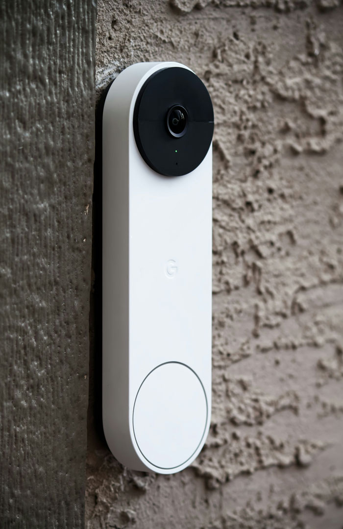 Smart video doorbell mounted on textured wall capturing moments of people home alone experiencing creepy events.