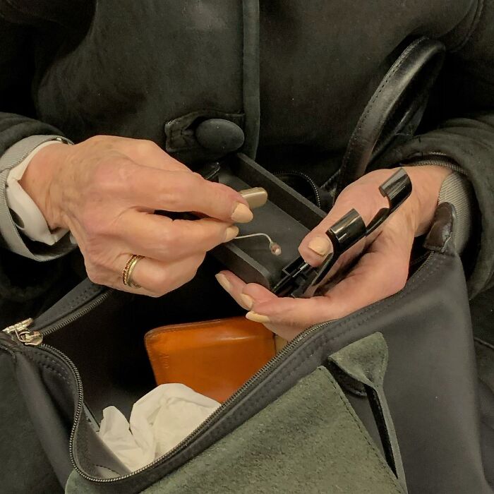 Person on New York subway holding a hearing aid and case, showcasing quirky items people carry on the subway.