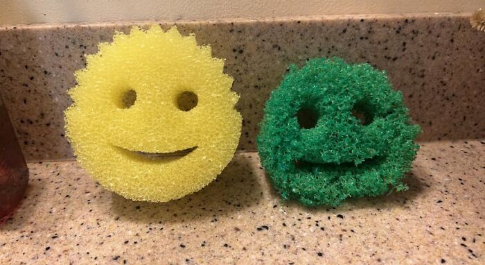 Two worn smiley face scrub sponges on a kitchen counter, illustrating companies sabotaging their own products.