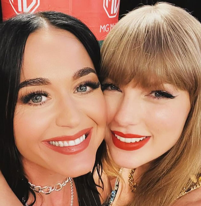 Close-up of two smiling women with makeup and red lipstick, related to Travis Kelce&rsquo;s answer about Taylor Swift topic.