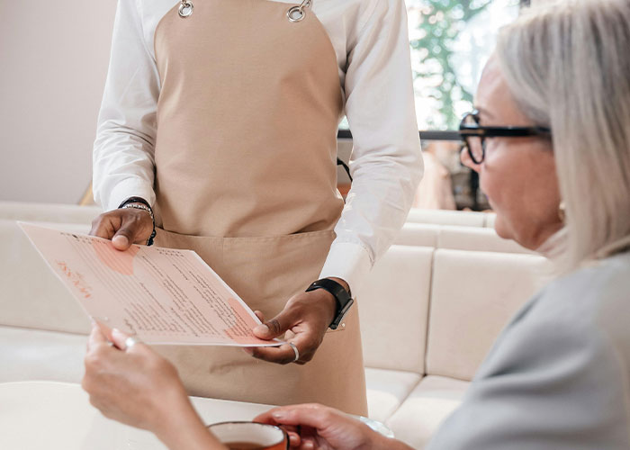 Waiter in apron showing menu to customer in a cafe, illustrating incredible coincidences that are hard to believe but true.