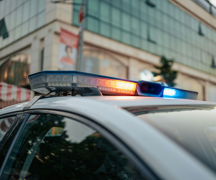 Police car with flashing lights parked on a city street related to diabolical couple arrested for hotboxing incident.