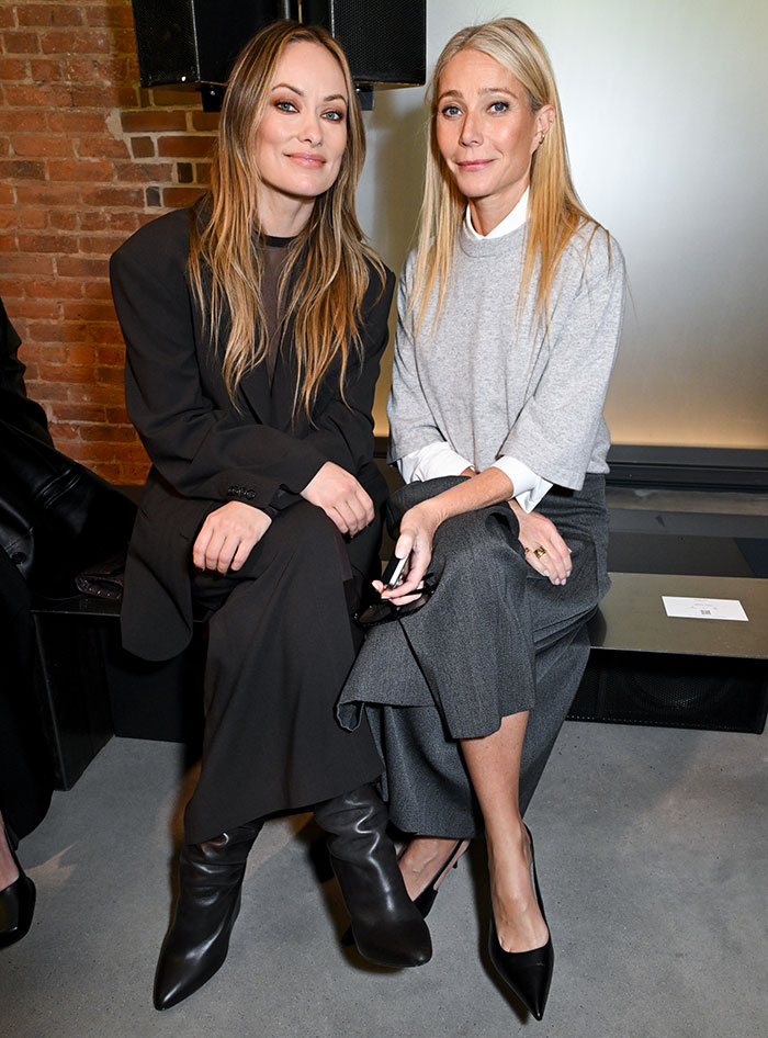 Olivia Wilde sitting in a sheer outfit without a bra, flashing toned abs during New York Fashion Week event.