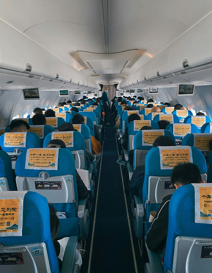 Airplane interior with passengers seated in blue seats showing a crowded cabin where a passenger attacks plus-size seatmate. Airplane interior with passengers seated in blue seats showing a crowded cabin where a passenger attacks plus-size seatmate.