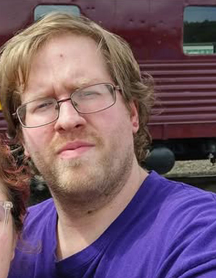 Man with glasses and light brown hair outdoors, linked to pastor's son accused of disturbing acts involving captive adults.