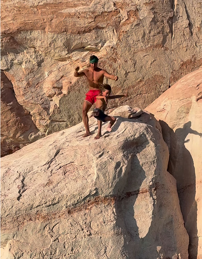 Man and young boy standing on a large rock cliff, capturing a moment related to dad who threw 7YO son off cliff incident. Man and young boy standing on a large rock cliff, capturing a moment related to dad who threw 7YO son off cliff incident.