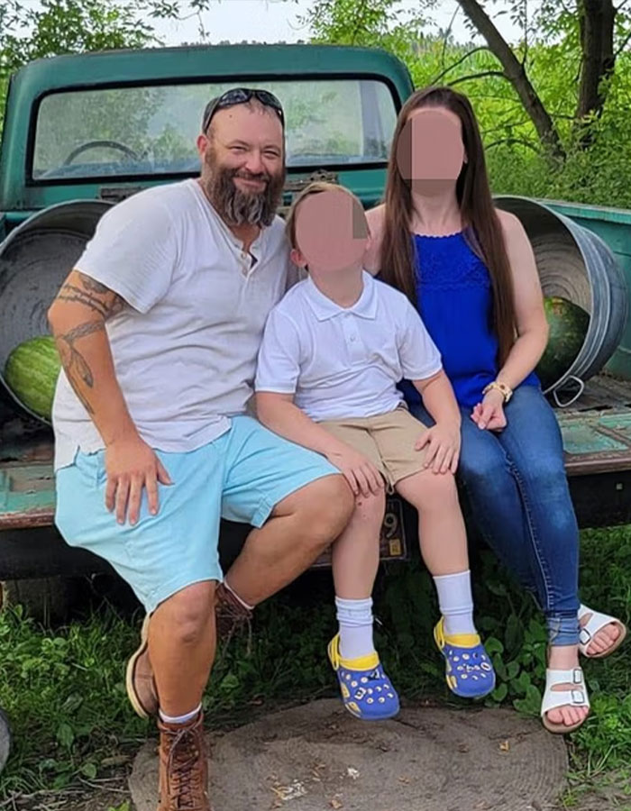 Michigan suspect with family sitting on a truck bed outdoors, faces blurred for privacy in a casual setting.