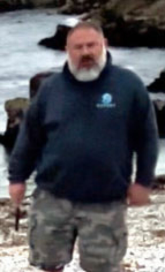 Man in camo shorts and dark sweatshirt near rocky California shore linked to sea lion incident with $20K reward offered.