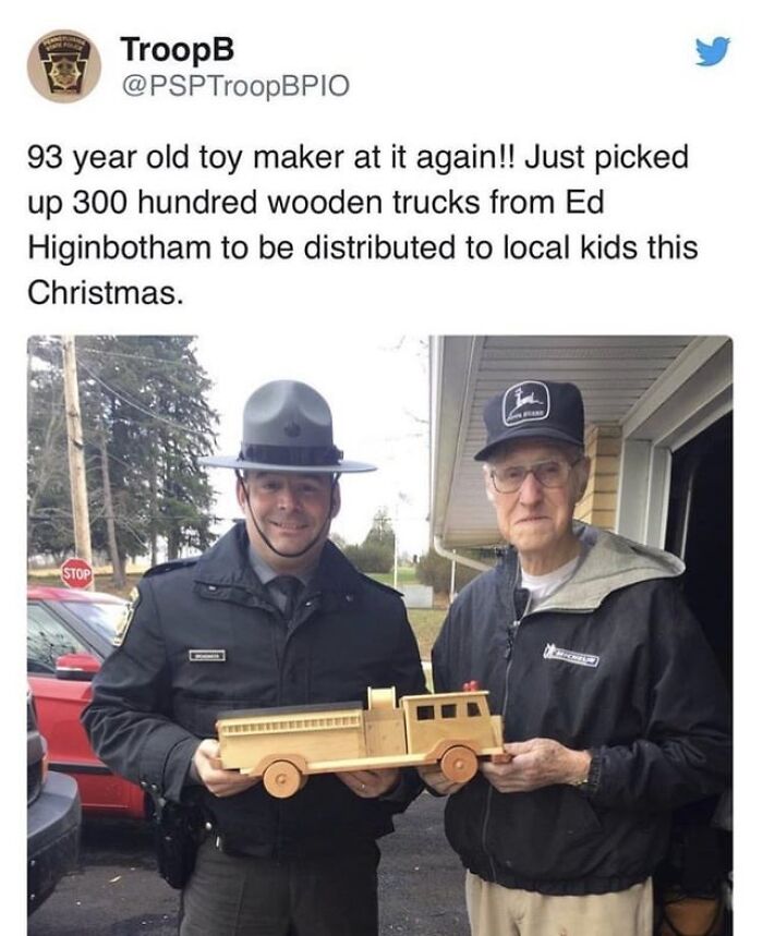 93-year-old toy maker and officer holding a handmade wooden truck in a wholesome post to distract from world horrors.