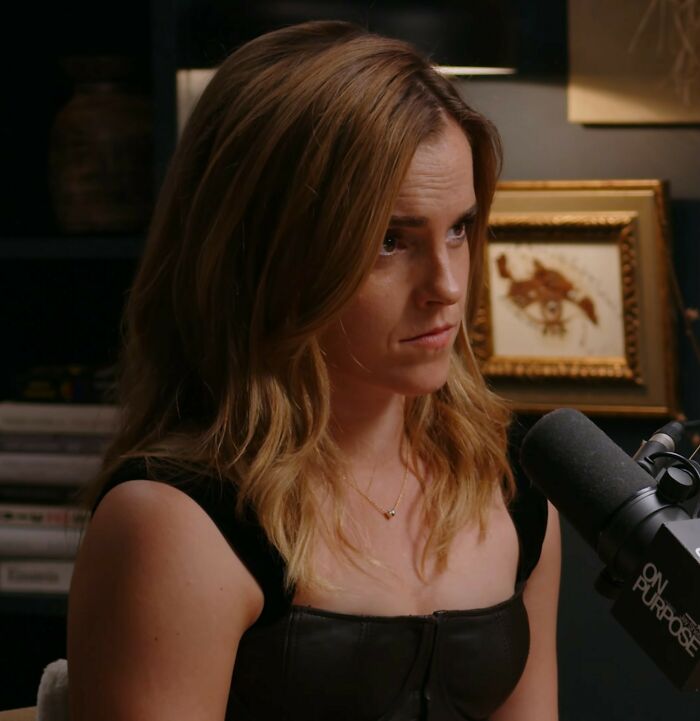 Emma Watson speaking into a microphone during a podcast, addressing the trans feud with J.K. Rowling.