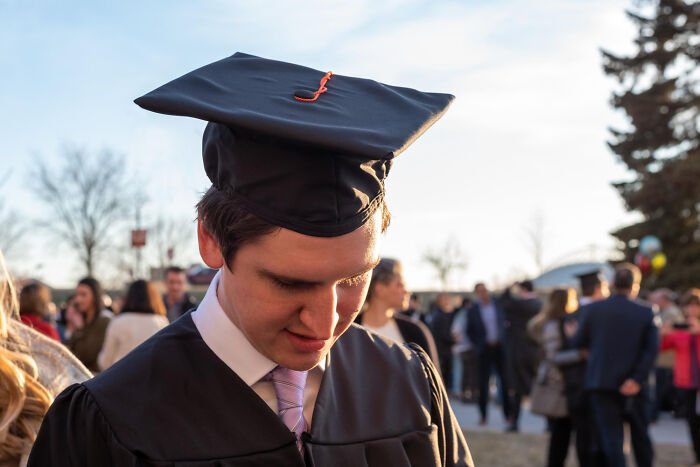 Young man in graduation cap and gown reflecting outdoors, symbolizing life-changing sentences tattooed on hearts.
