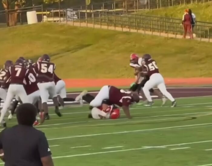 Football players in maroon and white uniforms on field during a high school game after a serious injury incident.