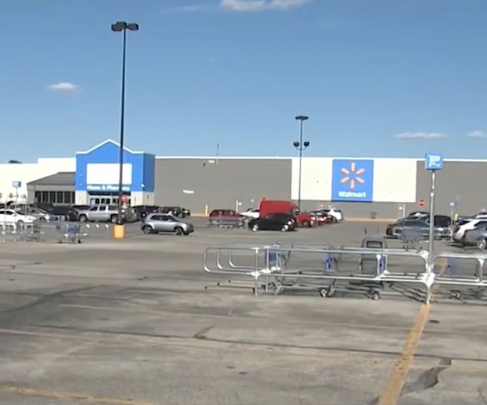Empty Walmart parking lot with parked cars under clear sky, relating to angry mob ambushing Walmart employee incident.