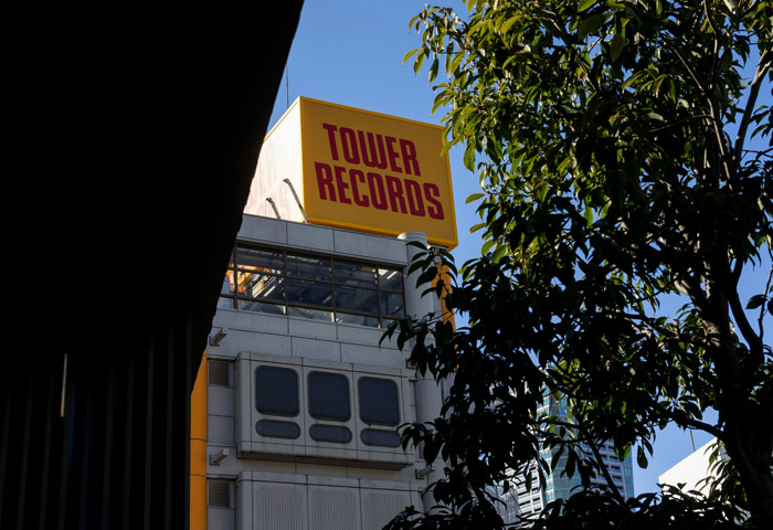 Tower Records building framed by shadows and tree branches under a clear sky, related to security guards and creepy job encounters.