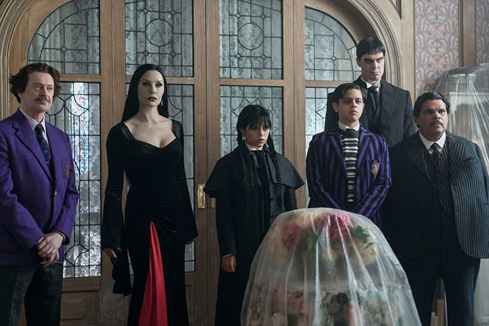 Group of six people in dark gothic attire standing in front of stained glass windows, linked to Catherine Zeta-Jones creepy comment.