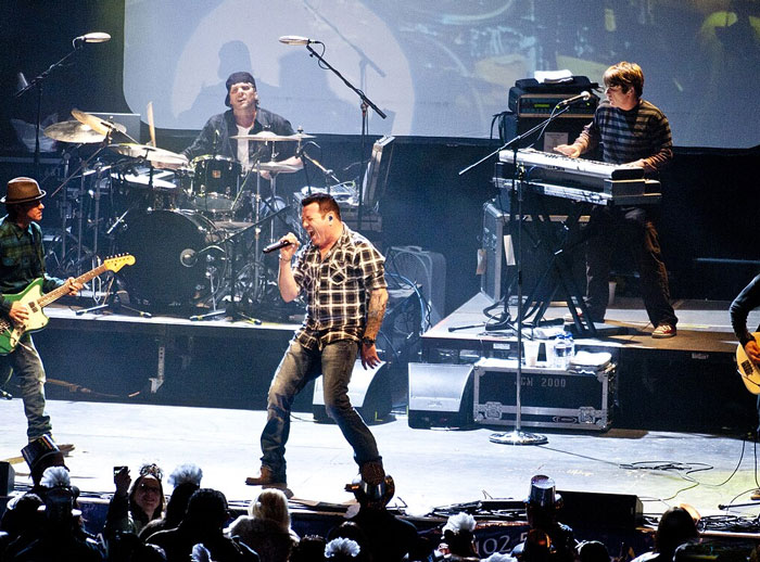 Band performing live on stage with crowd watching during a concert experience and music event.