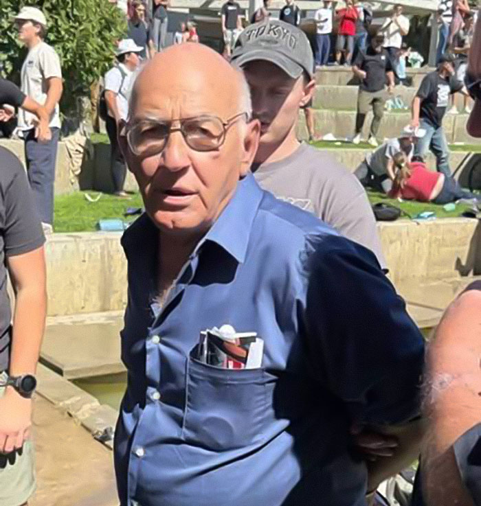 Man in blue shirt and glasses detained by crowd, related to false confession about Charlie Kirk's assassin case. Man in blue shirt and glasses detained by crowd, related to false confession about Charlie Kirk's assassin case.