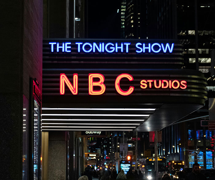 NBC Studios marquee for The Tonight Show illuminated at night, relating to Jimmy Fallon and show suspension news.