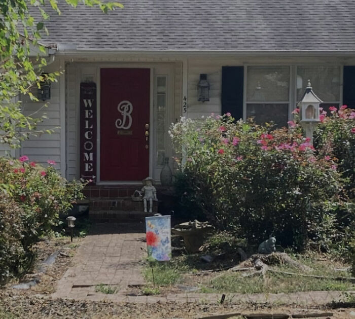 Front view of a suburban house with a red door surrounded by bushes related to pastor's son captive basement case.