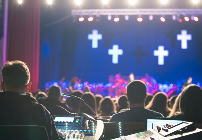 Audience watching a live music event with sound technicians working, highlighting groups of people and common sense challenges.