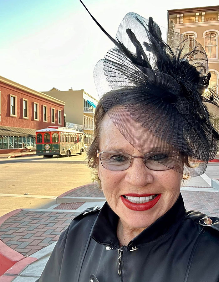 Woman wearing glasses and a black hat outdoors, sharing symptoms her doctor misunderstood before cancer diagnosis.