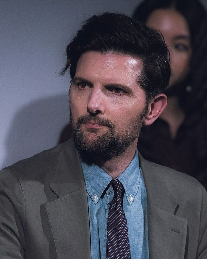 Man with dark hair and beard wearing a suit and tie, representing people running into celebrities and worst experiences.