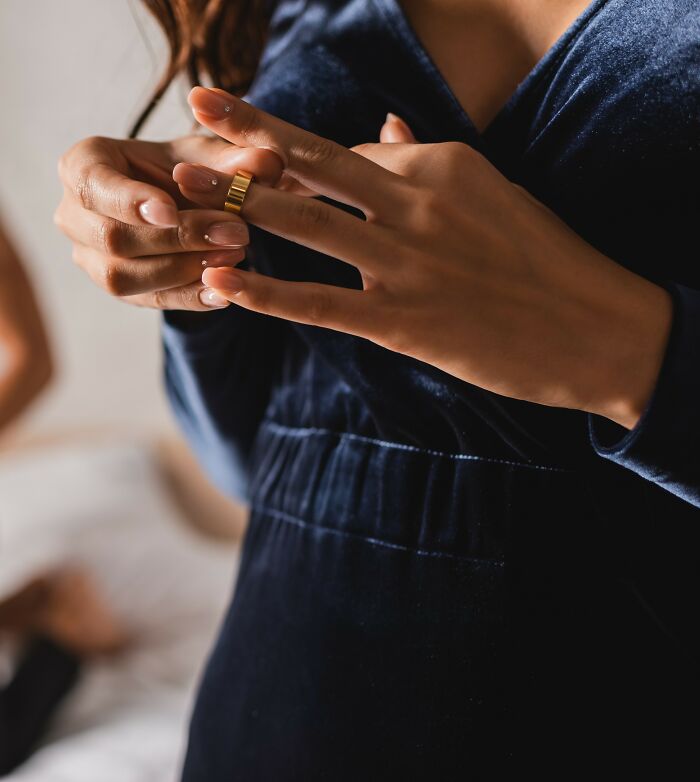 Close-up of a new bride wearing a dark dress, holding a ring, symbolizing wedding week and relationship drama. Close-up of a new bride wearing a dark dress, holding a ring, symbolizing wedding week and relationship drama.