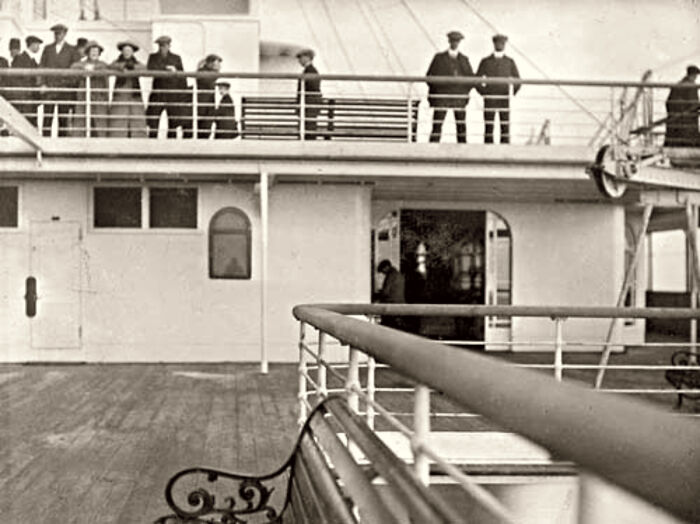 Rare historical photo of the Titanic deck showing passengers and crew standing along the railing on a clear day.