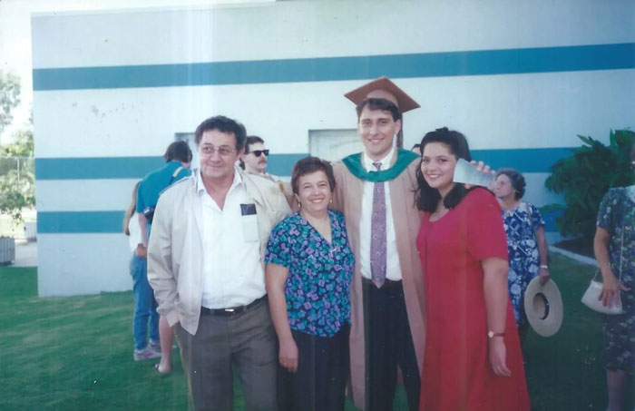 Young man in graduation gown celebrating with family outdoors, related to testicular cancer and surprising pregnancy blood tests.
