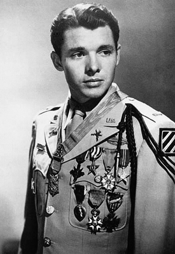 Young American folk hero in military uniform adorned with numerous medals and decorations, looking pensively to the side.