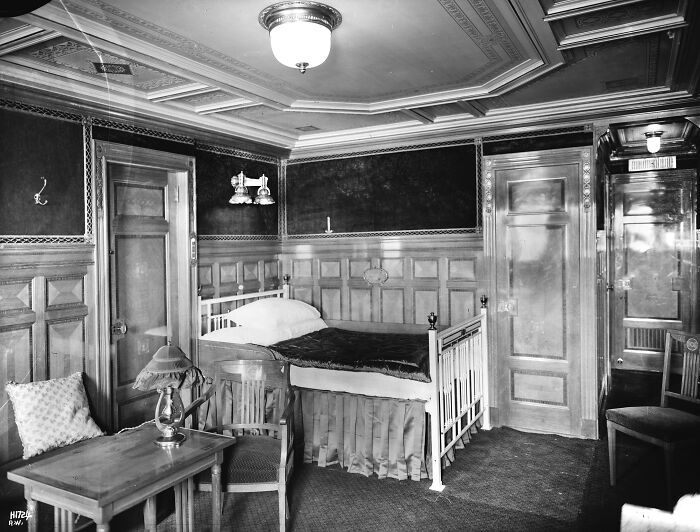 Historic Titanic cabin interior showing period furniture and detailed wood paneling in a rare historical photo.