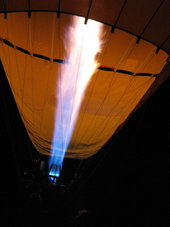 Hot air balloon burner flame glowing brightly inside the balloon at night, showing real life bizarre and interesting moments.