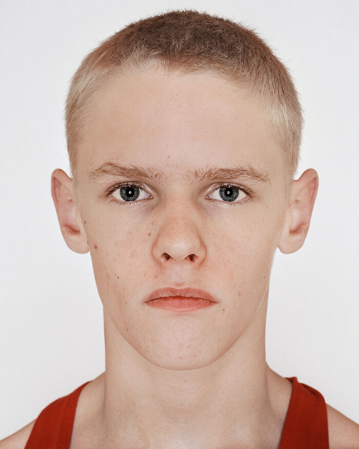 Close-up portrait of a young boxer with short hair wearing a red tank top before his first match showing determination.