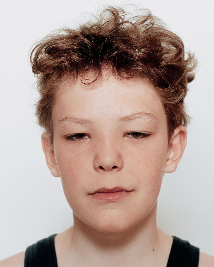 Close-up portrait of a young boxer with curly hair, showing calm confidence before their first match.