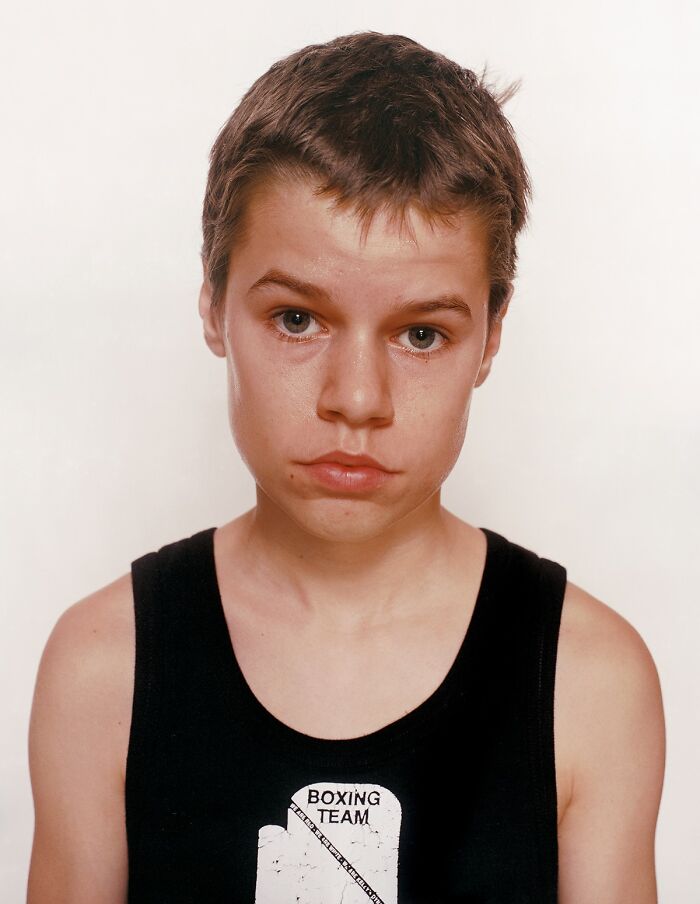 Young boxer wearing a black tank top with boxing team logo, showing determination before his first match.