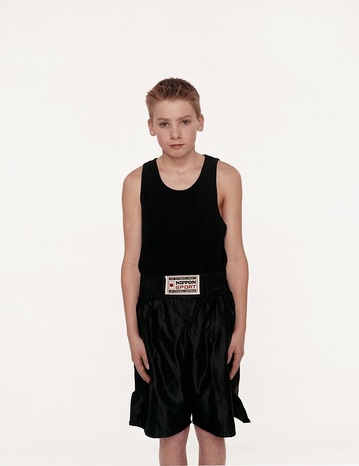 Young boxer in black sportswear posing before his first match with a serious expression on a plain white background.