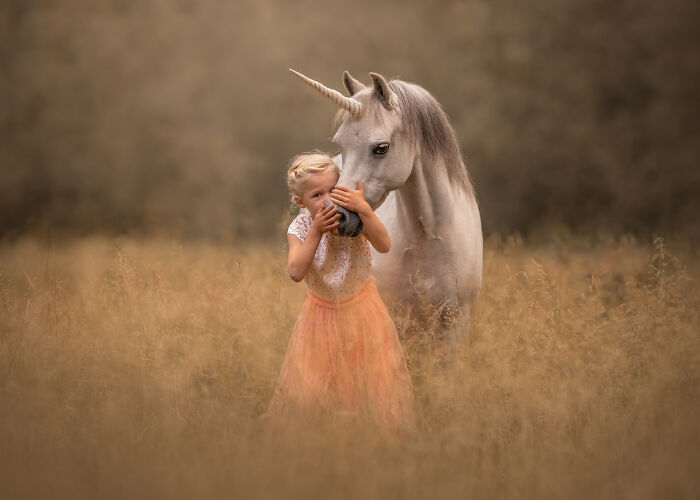 Young girl hugging a white unicorn pet in a field, a creative pet photo with heartwarming tones winning photography awards.