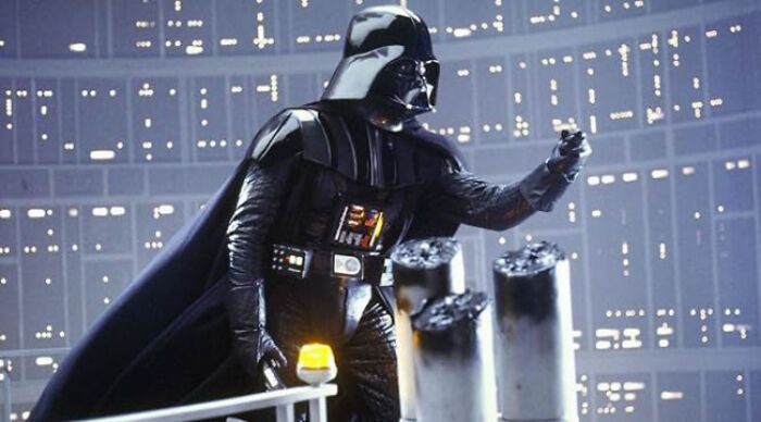 Darth Vader in black armor and cape using the force in a sci-fi setting illustrating popular movie tropes.