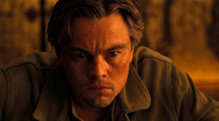 Close-up of a man with a serious expression in a dimly lit setting, representing popular movie tropes in film scenes.