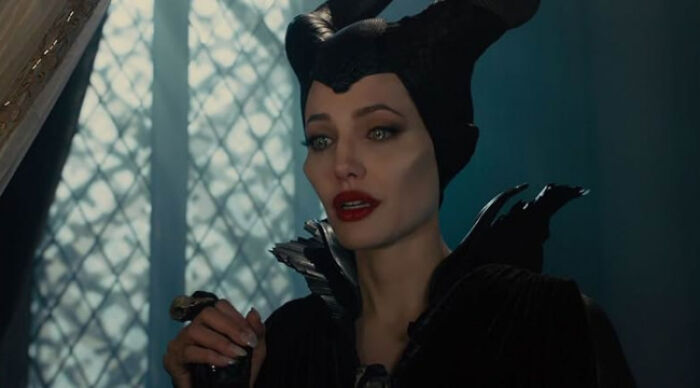 Woman dressed as a dark fairy character in a movie scene, representing beloved movie tropes in a cinematic poll.
