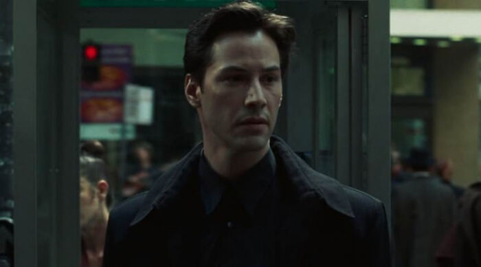 Actor in a dark coat walking through a revolving door, illustrating beloved movie tropes in a dramatic scene.