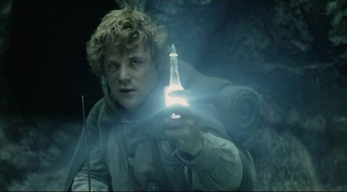 Character in a dark cave holding a glowing bottle, illustrating beloved movie tropes in film storytelling and polls.