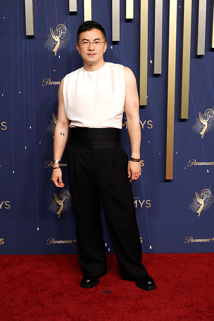 Person wearing a sleeveless white top and black pants posing on the red carpet at the 2025 Emmys fashion event.